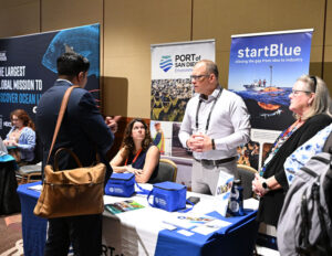 A potential entrepreneur talks to StartBlue representatives at their table at a networking event.